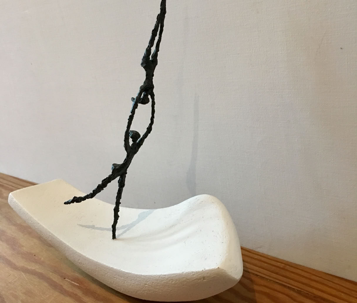 Bronze-Akrobaten machen Partneraktobatik, bei der eine Figur einen Handstand auf den ausgestreckten Armen der anderen macht.